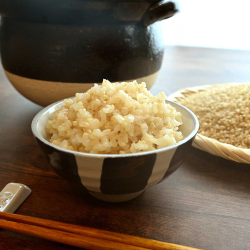 お茶碗に盛られた玄米ごはんと箸と土鍋